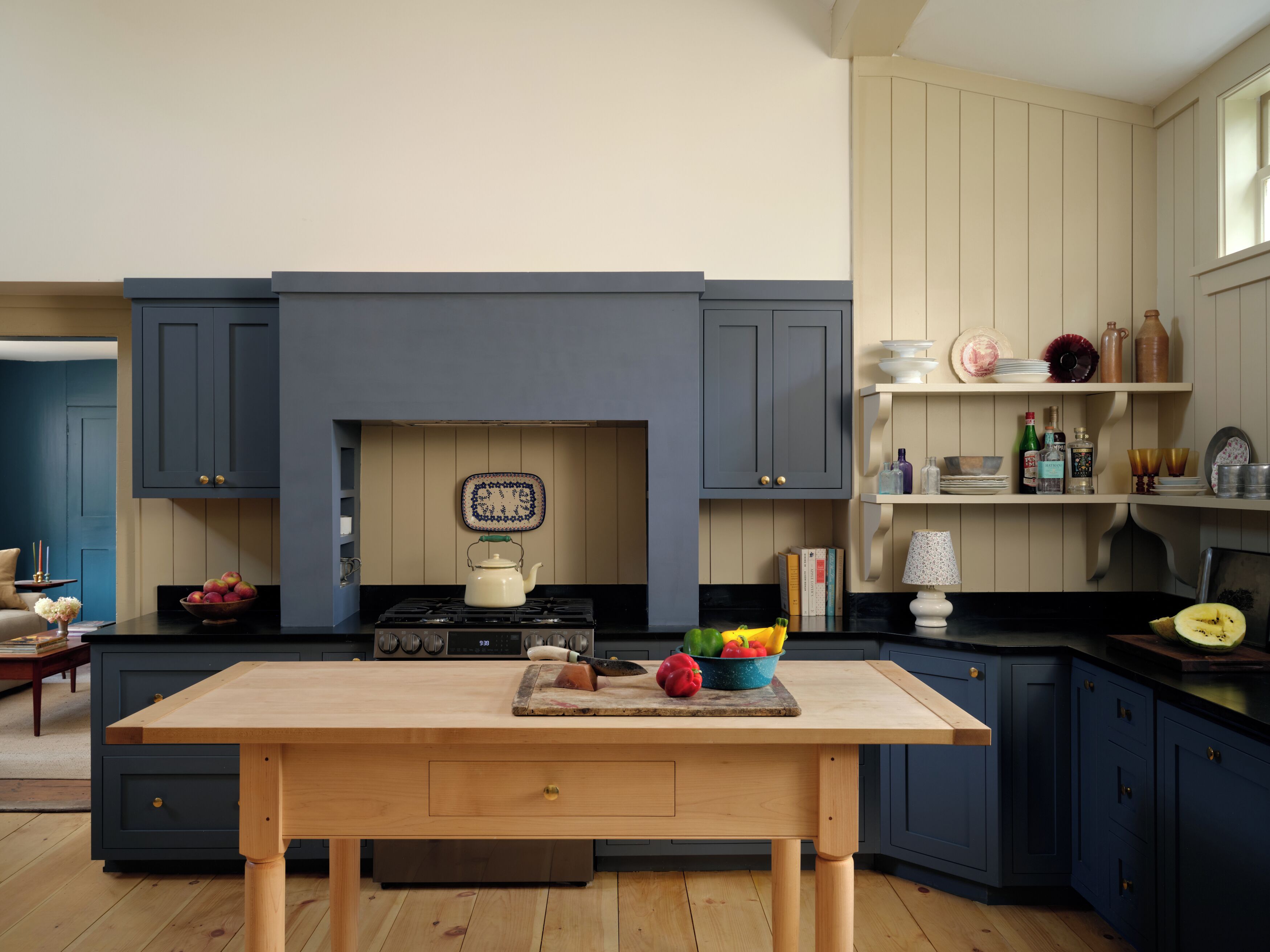A modern kitchen with dark blue cabinets, a wooden table, and various kitchen items.