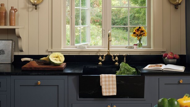 Una cocina con ventana, un lavamanos y diversos utensilios.