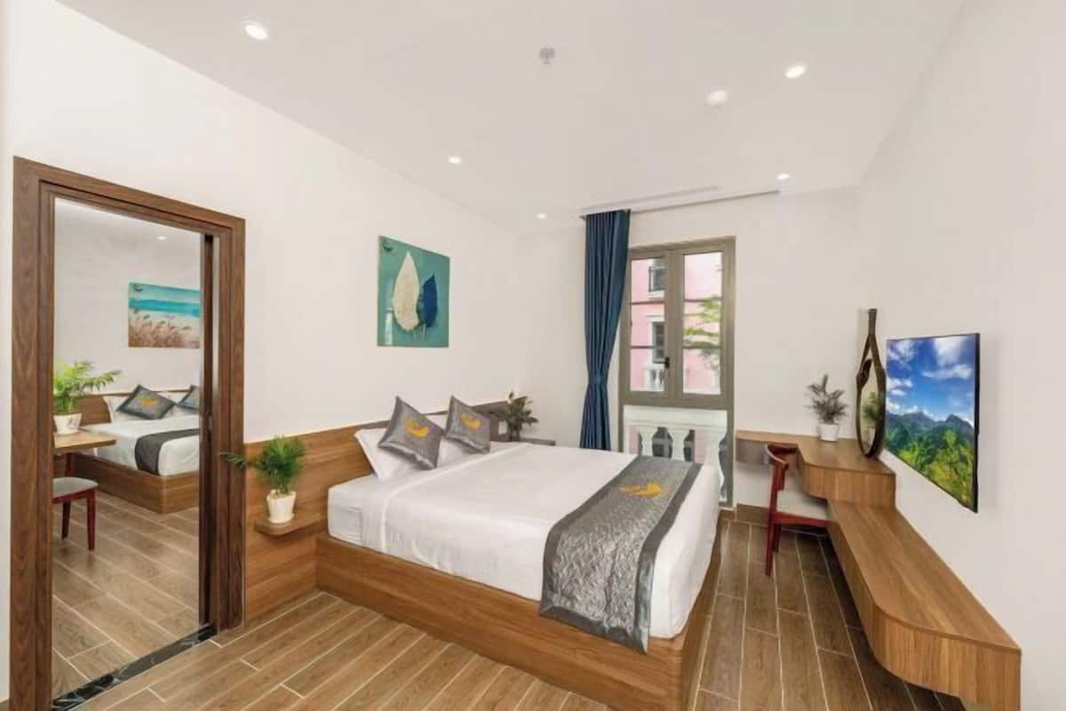 A modern bedroom with a wooden bed, a desk, and a large window.