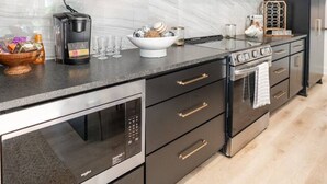 A modern kitchen with dark cabinetry, a built-in oven, and a coffee maker. - Luxury Getaway in East Texas, Pool • Jacuzzi (Bullard)