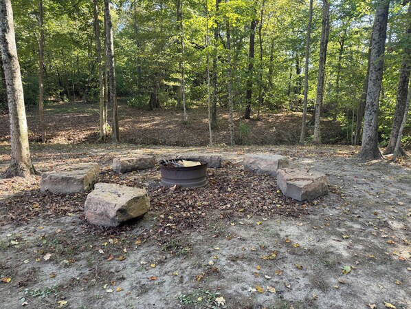Campsite arbolado con un brasero rodeado de rocas.