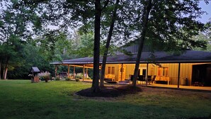 A house with a covered porch, a lawn, and a birdhouse.