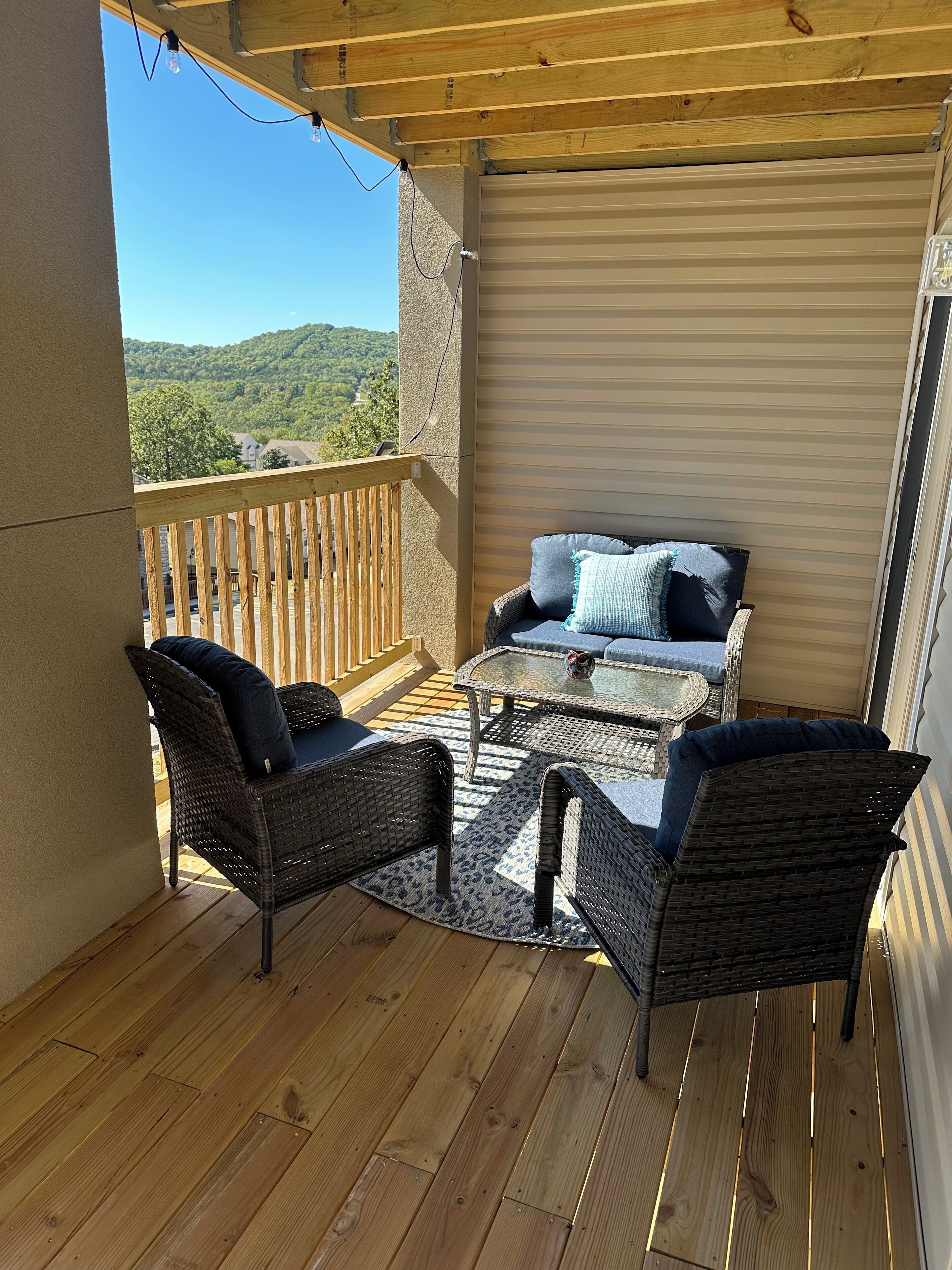 A covered outdoor seating area with wicker furniture and a view of a mountainous landscape.