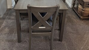 Ein Esszimmer mit einem rechteckigen Tisch, sechs Stühlen, einer Schale mit Dekorationsobjekten und einem Fenster mit Jalousien.