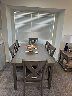 A dining room with a rectangular table, six chairs, a bowl of decorative items, and a window with blinds. - Beautiful Brand new! NO STAIRS Next to SDC! 2 king rooms queen sofa 2 full baths (Branson)