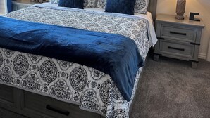 Ein Schlafzimmer mit einem Bett, Nachttischen, einem Deckenventilator und einem Fenster mit Vorhängen.