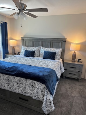 A bedroom with a bed, nightstands, a ceiling fan, and a window with curtains. - Beautiful Brand new! NO STAIRS Next to SDC! 2 king rooms queen sofa 2 full baths (Branson)