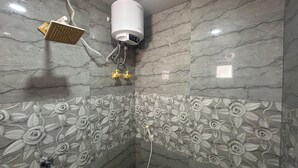 A bathroom with a shower, a handheld showerhead, and a wall-mounted water heater. - Rc Stays (Noida)