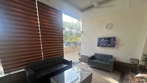 A modern living room with a glass coffee table, two sofas, and a TV mounted on the wall. - Rc Stays (Noida)