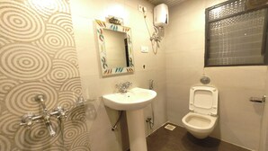 A bathroom with a sink, mirror, toilet, and a shower. - Hotel Shreeyash Executive (Pune)