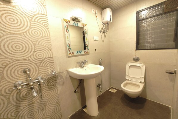 A bathroom with a sink, mirror, toilet, and a shower. - Hotel Shreeyash Executive (Pune)