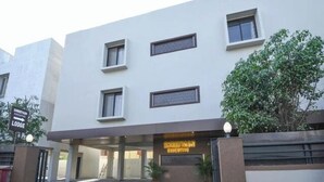 A modern building with a flat facade, multiple windows, and a sign indicating a lodge. - Hotel Shreeyash Executive (Pune)