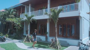 A two-story building with a balcony, a paved driveway, and a motorcycle parked in front.