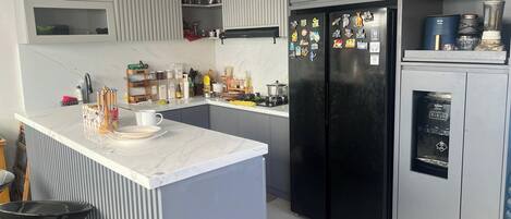 Una cocina moderna con armarios grises, un refrigerador negro y un microondas integrado.
