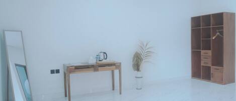 A minimalist room with a wooden table, a mirror, a potted plant, and a wardrobe.