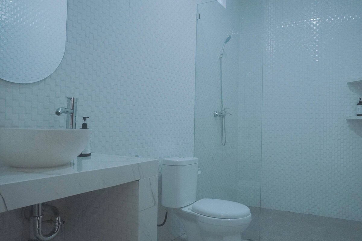 A bathroom with a white sink, toilet, and shower.
