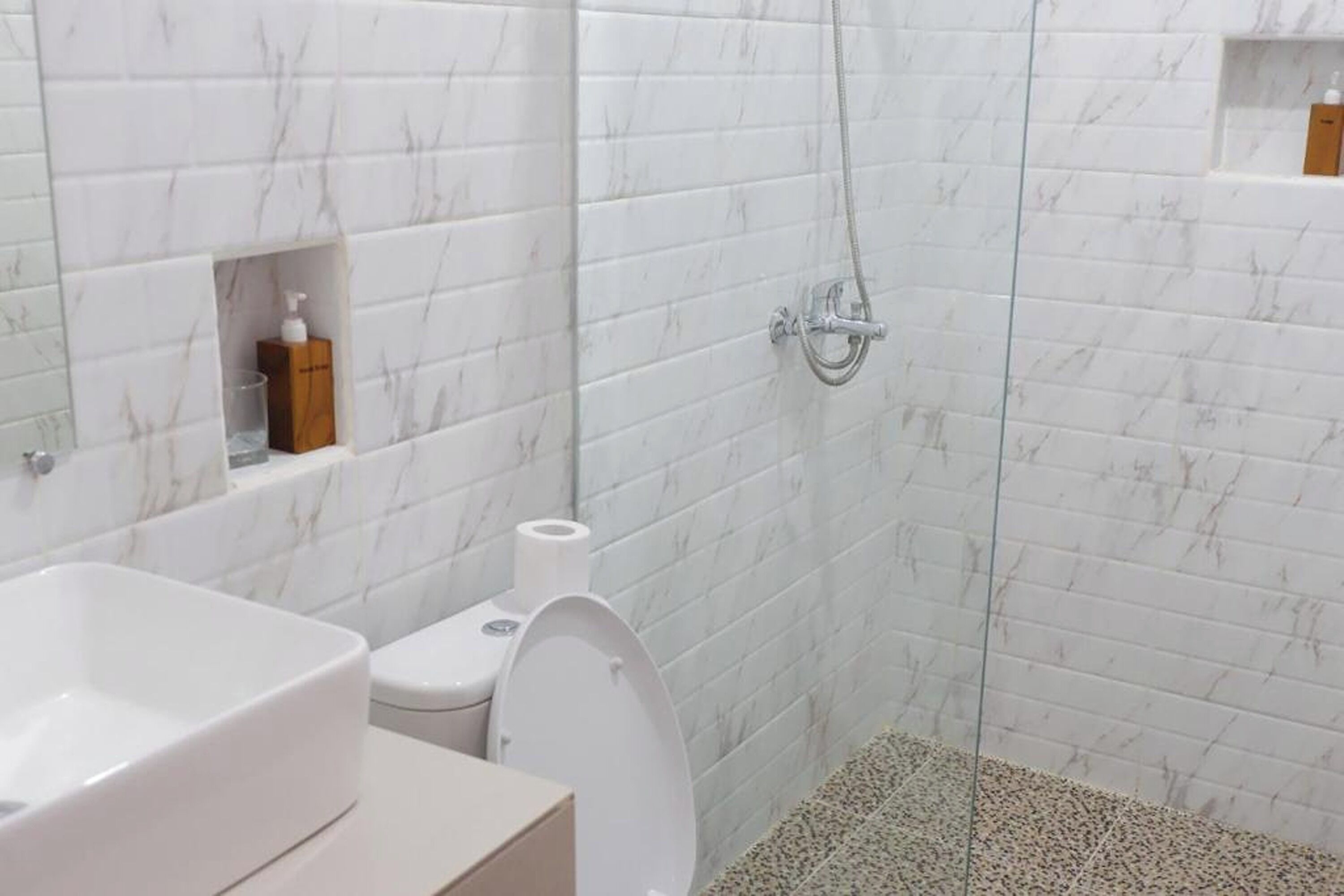Et badeværelse med bruser, toilet og håndvask.
