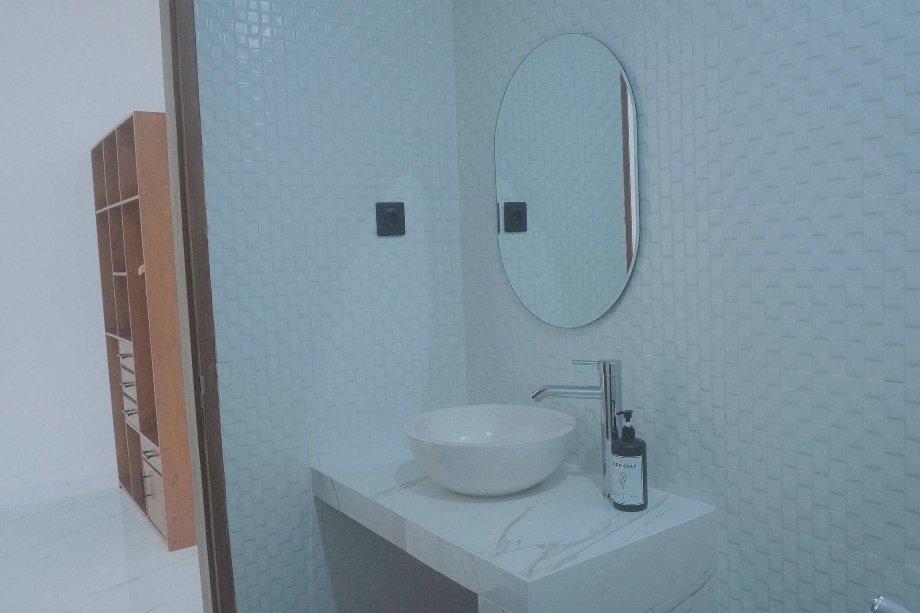 Une salle de bain avec un lavabo blanc, un miroir et un distributeur de savon.