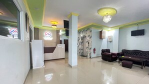 A hotel lobby with a reception desk, a staircase, a sofa, and a fire extinguisher. - Blissful Executive Kost (Medan)
