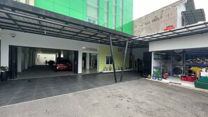 A parking area with a car, a building with a green facade, and a laundry service shop. - Blissful Executive Kost (Medan)