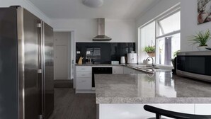 A modern kitchen with a stainless steel refrigerator, a built-in oven, and a large window providing natural light. - Modern Ease in East Devonport (City of Devonport)