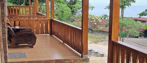 A wooden deck with a view of the ocean, a wooden table and chairs, and a small seating area with a bench.