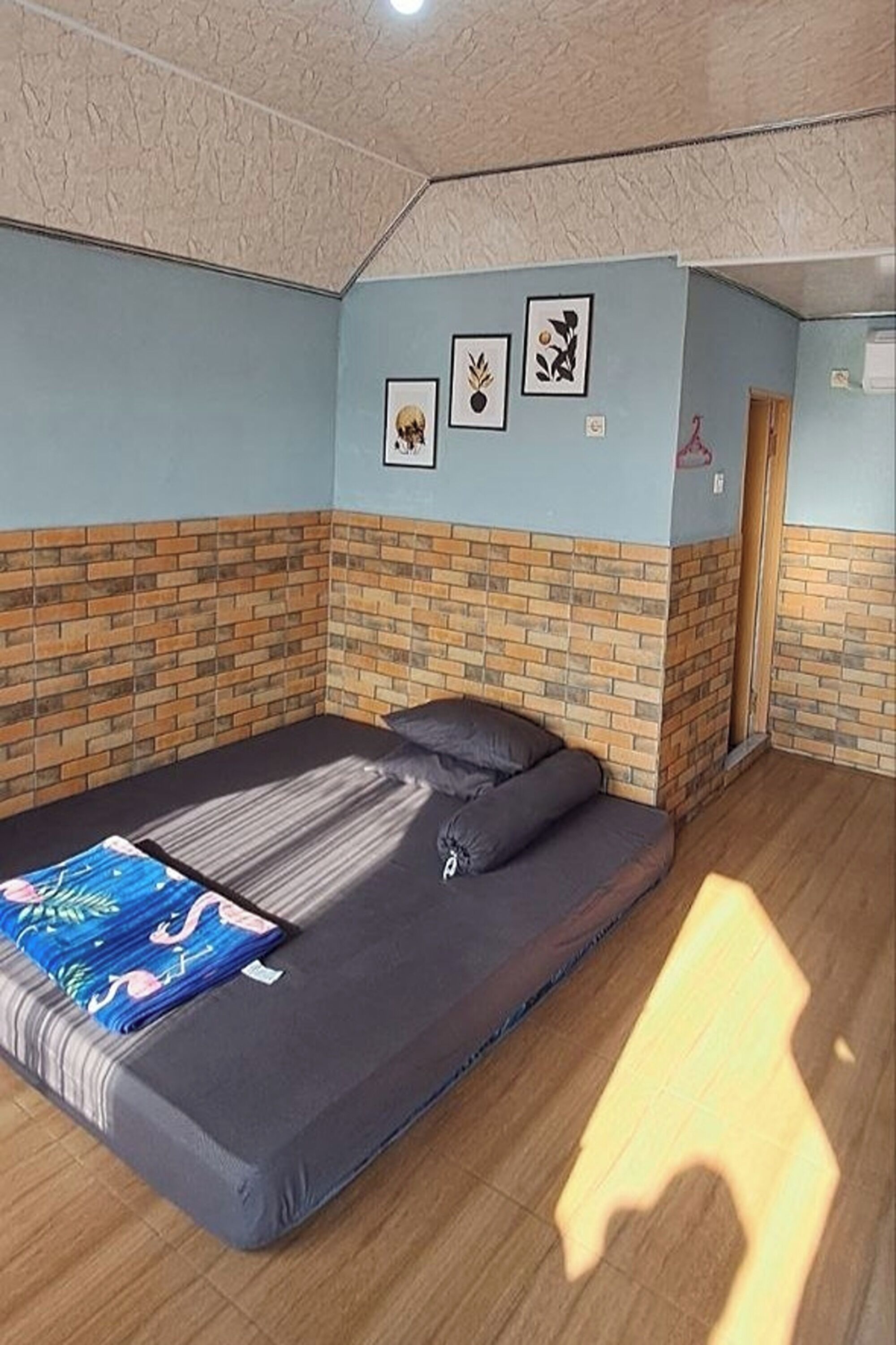 Ein Zimmer mit einem Bett, einer Ziegelwand und einer Tür.