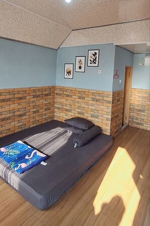 A room with a bed, a brick wall, and a door. - Griya Prasetaya (Wonosari)