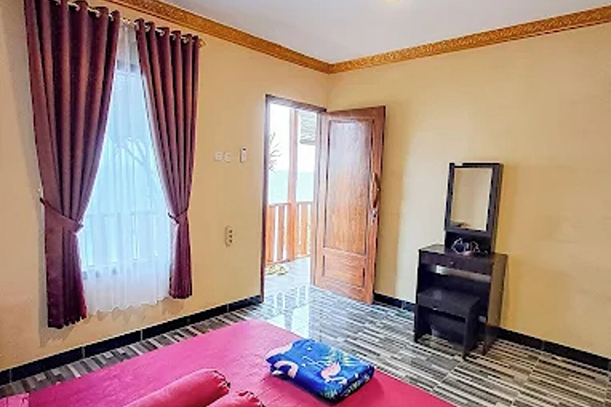 A room with a bed, a mirror, and a door leading outside.