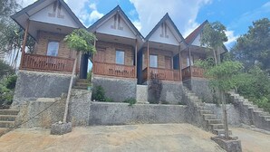 A row of three identical houses with wooden balconies and stone steps leading up to the entrance. - Griya Prasetaya (Wonosari)
