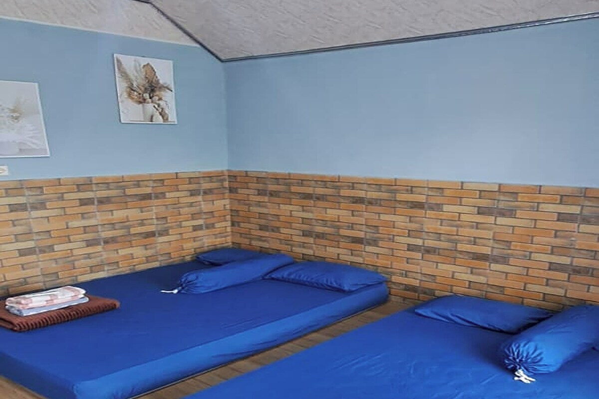 A room with two beds, a brick wall, and a ceiling fan.