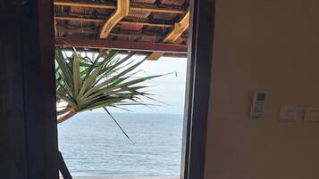 Habitación con vista al mar, balcón de madera, zona de cocina con hervidor y suelo estampado.