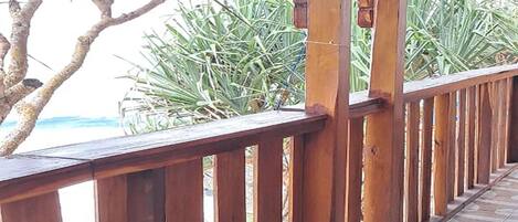 A wooden deck with a tiled floor, surrounded by palm trees and a view of the ocean.