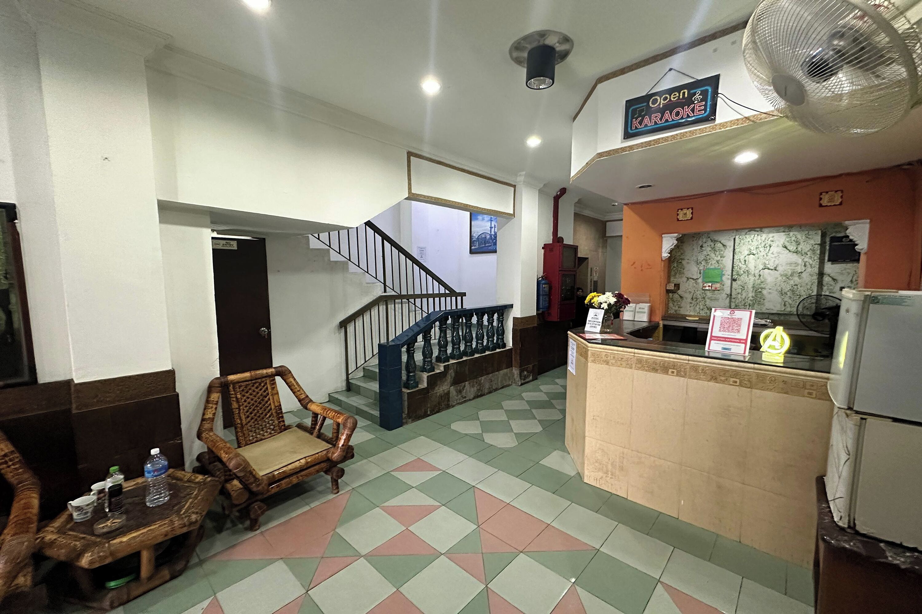 A hotel lobby with a check-in counter, a staircase, and seating area.