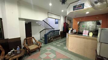 A hotel lobby with a check-in counter, a staircase, and seating area.