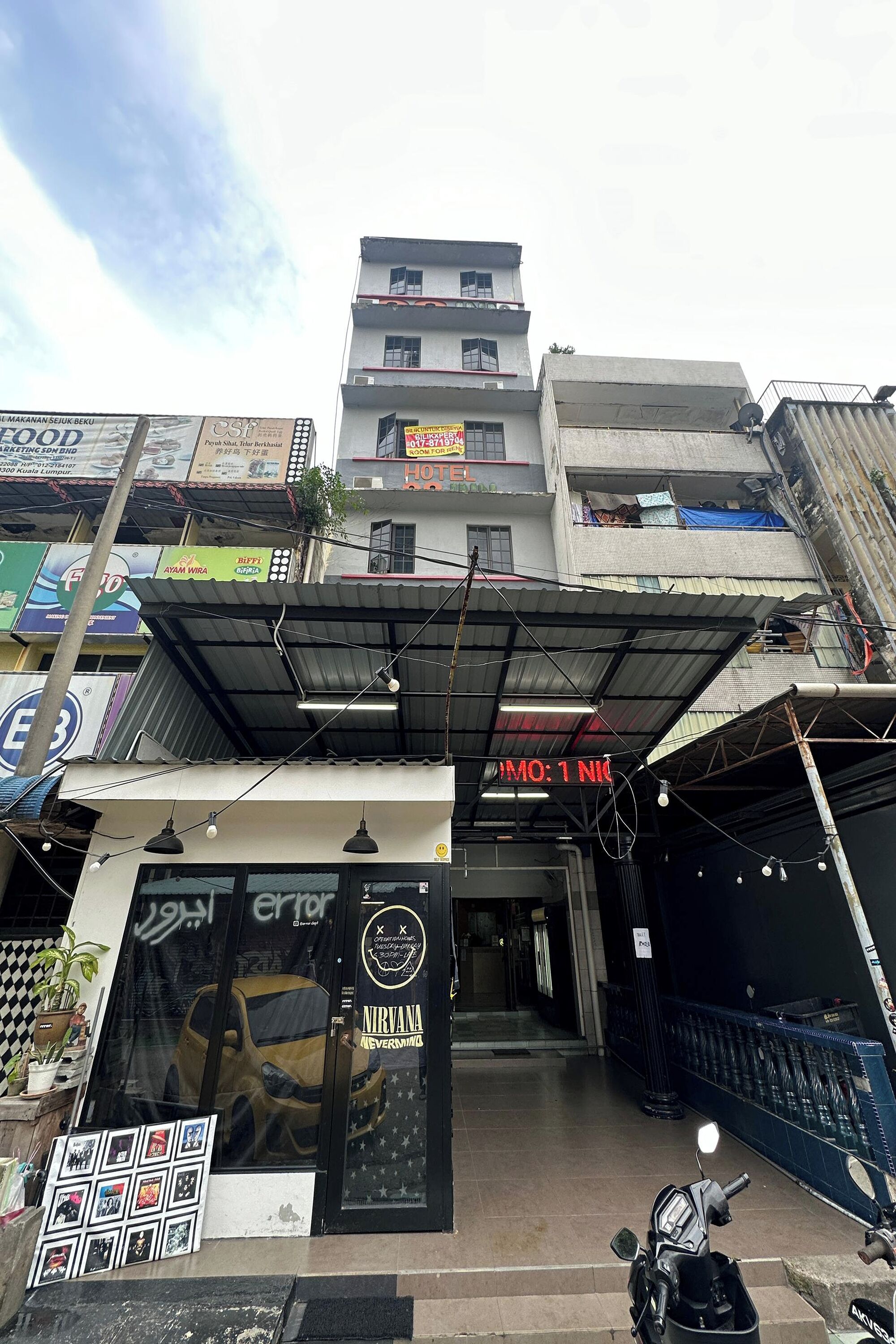 A building with a sign reading "HOTEL" and a car parked in front.