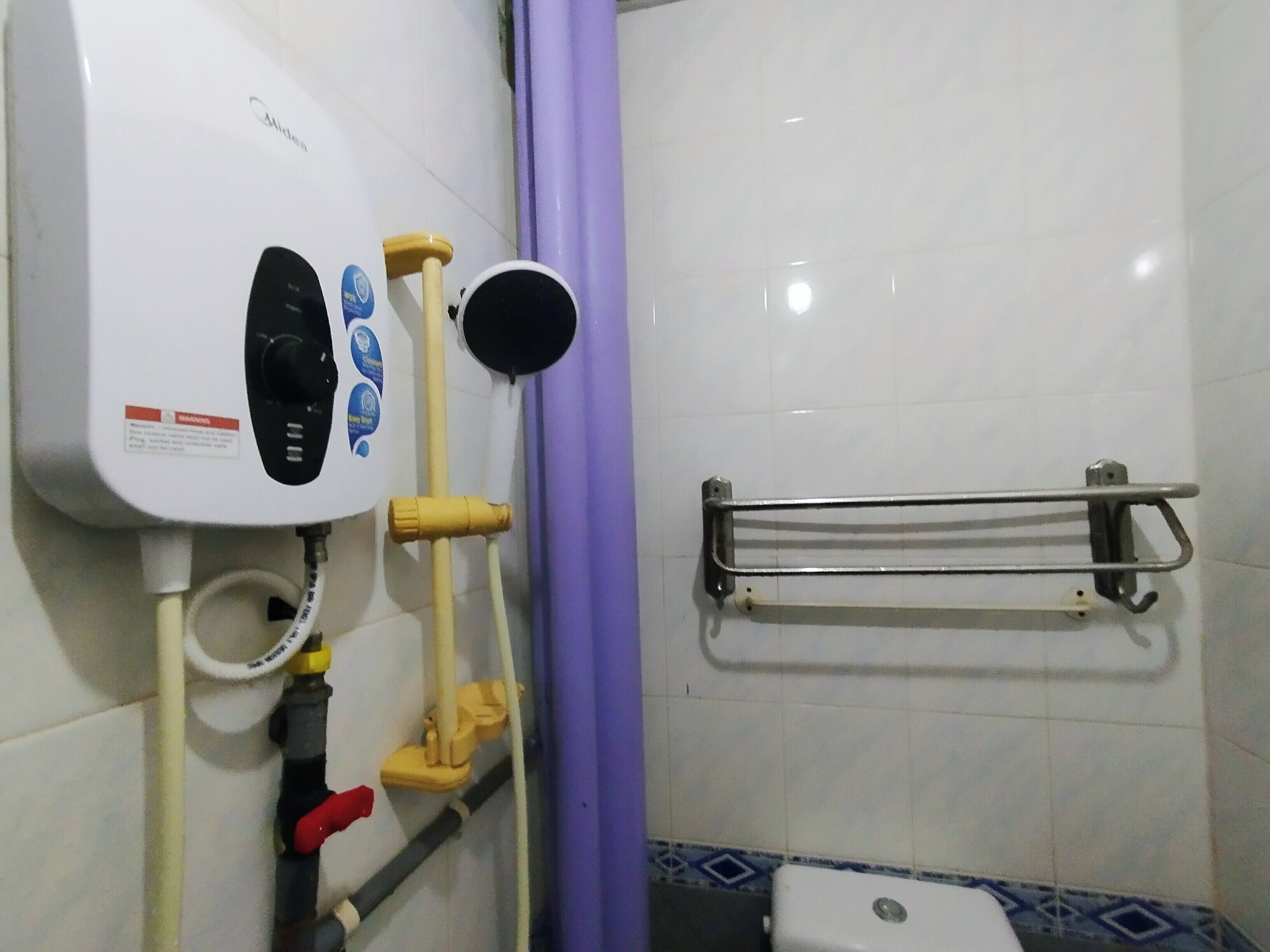 A bathroom with a toilet, a hand dryer, and a towel rack.