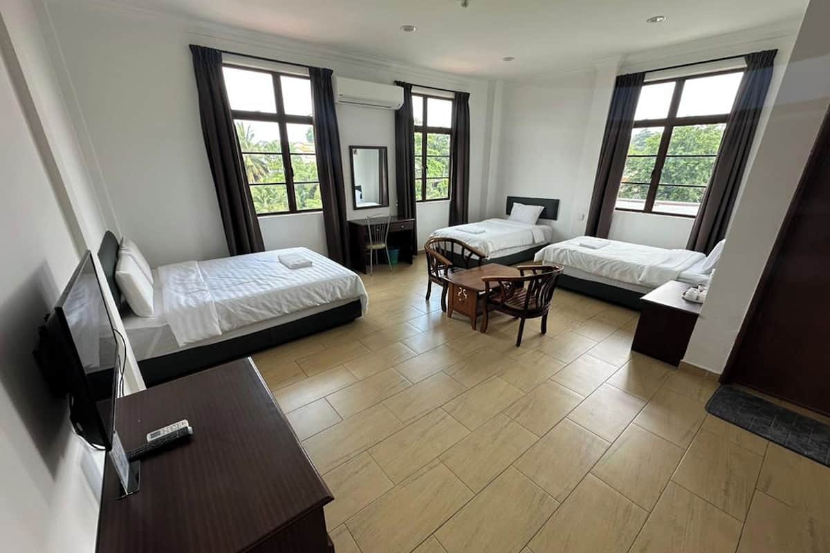 Ett hotellrum med två sängar, ett skrivbord, en stol och stora fönster.
