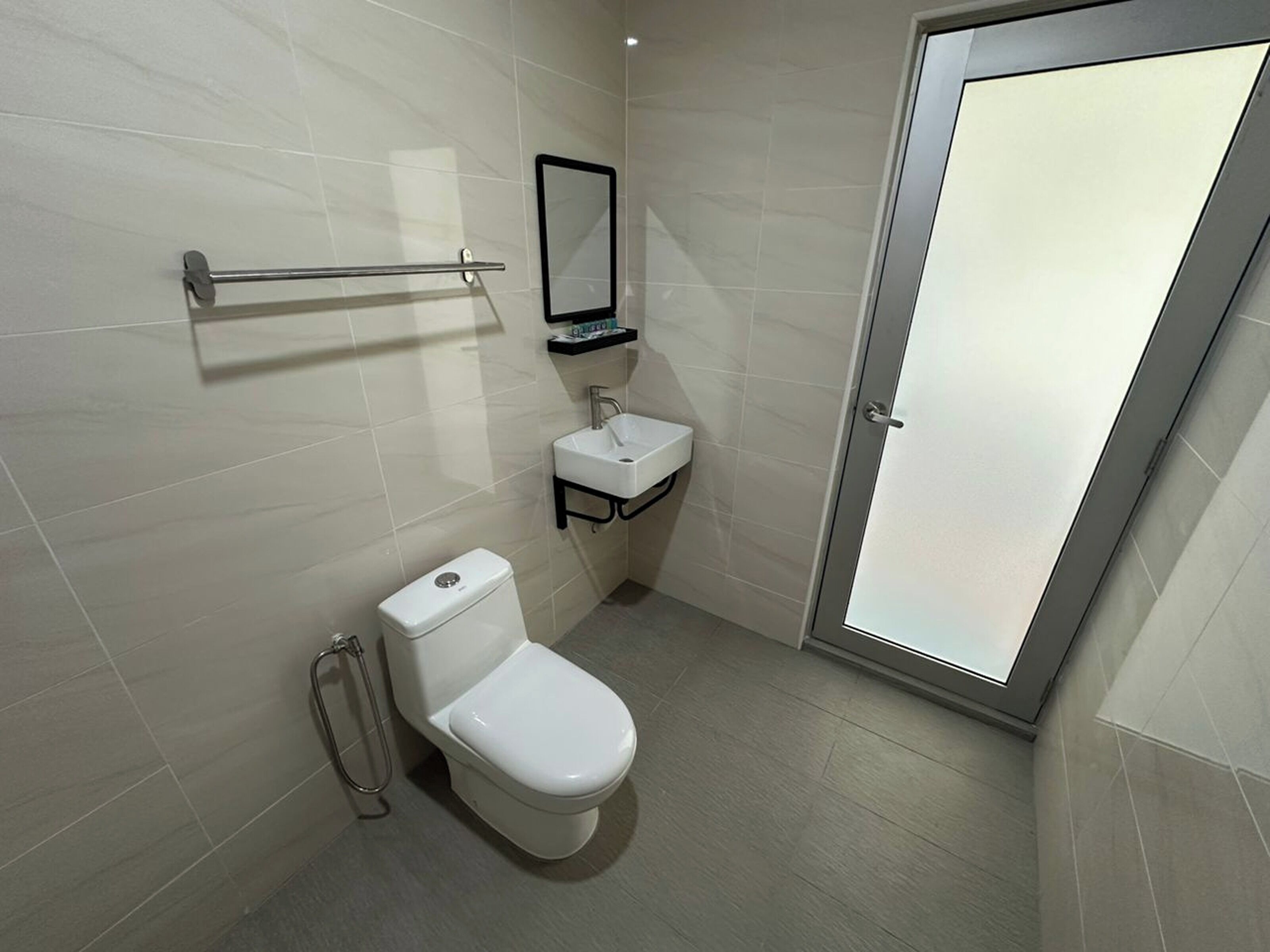 A modern bathroom with a toilet, sink, and a glass shower door.