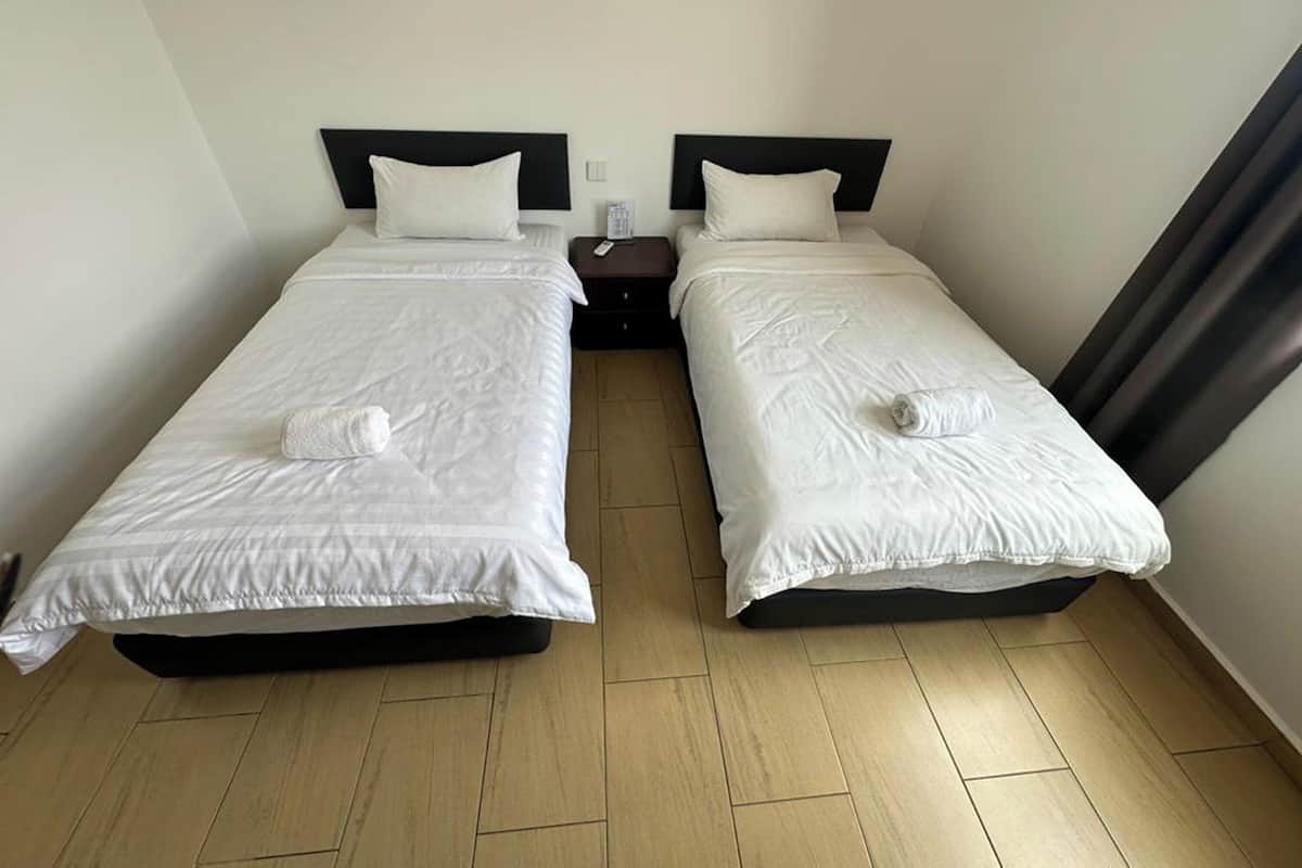 Ett hotellrum med två separata sängar, var och en med en svart sänggavel och vitt sänglinne.