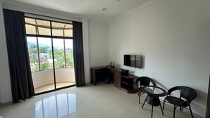 A modern room with a large window, a flat-screen TV, a small desk, and two chairs. - Glistar Hotel (Tampin)