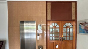 An elevator, a wooden double door with glass panels, and a trash bin in a hallway. - Glistar Hotel (Tampin)