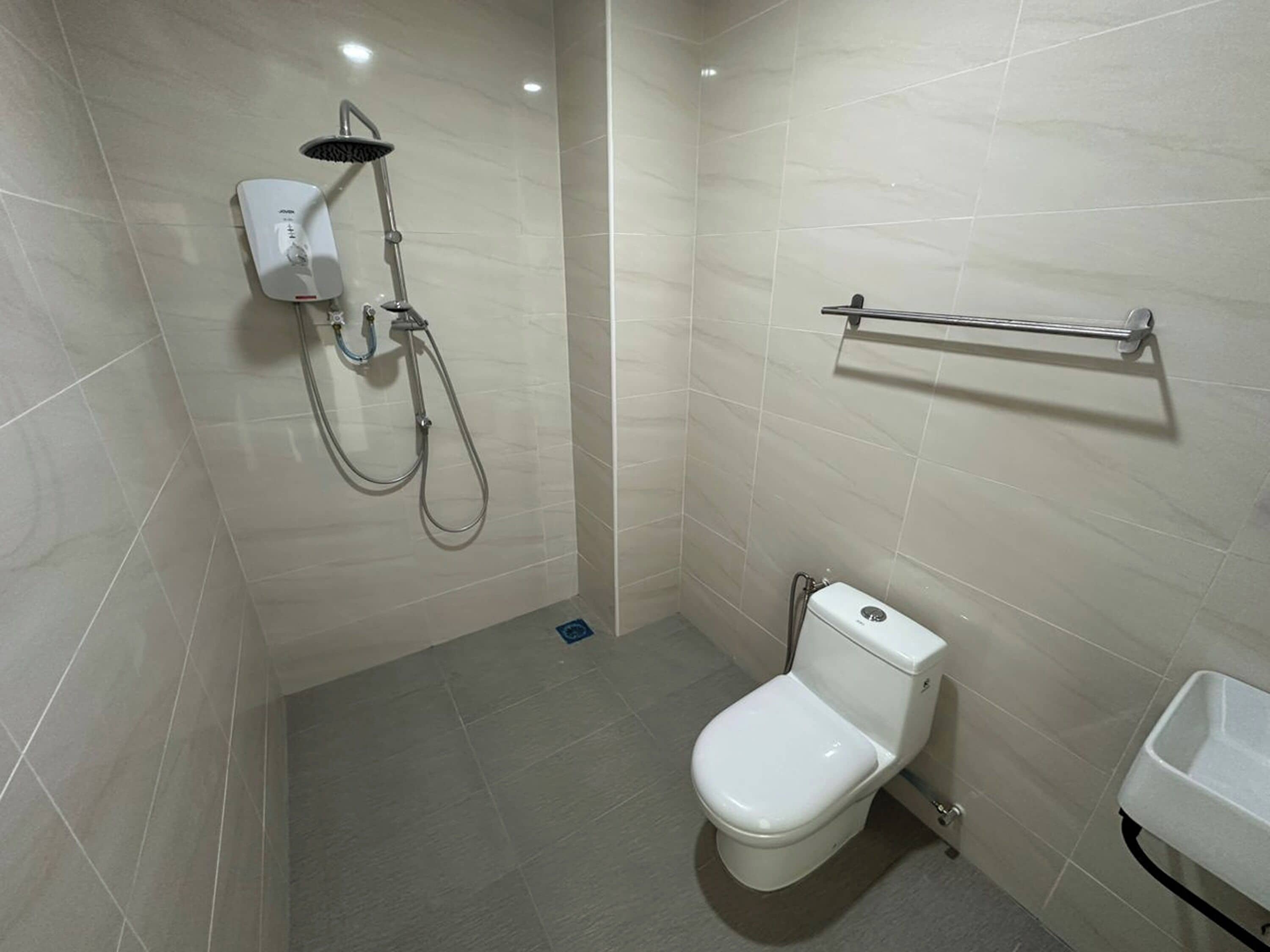 Un baño pequeño y moderno con inodoro, ducha y toallero.