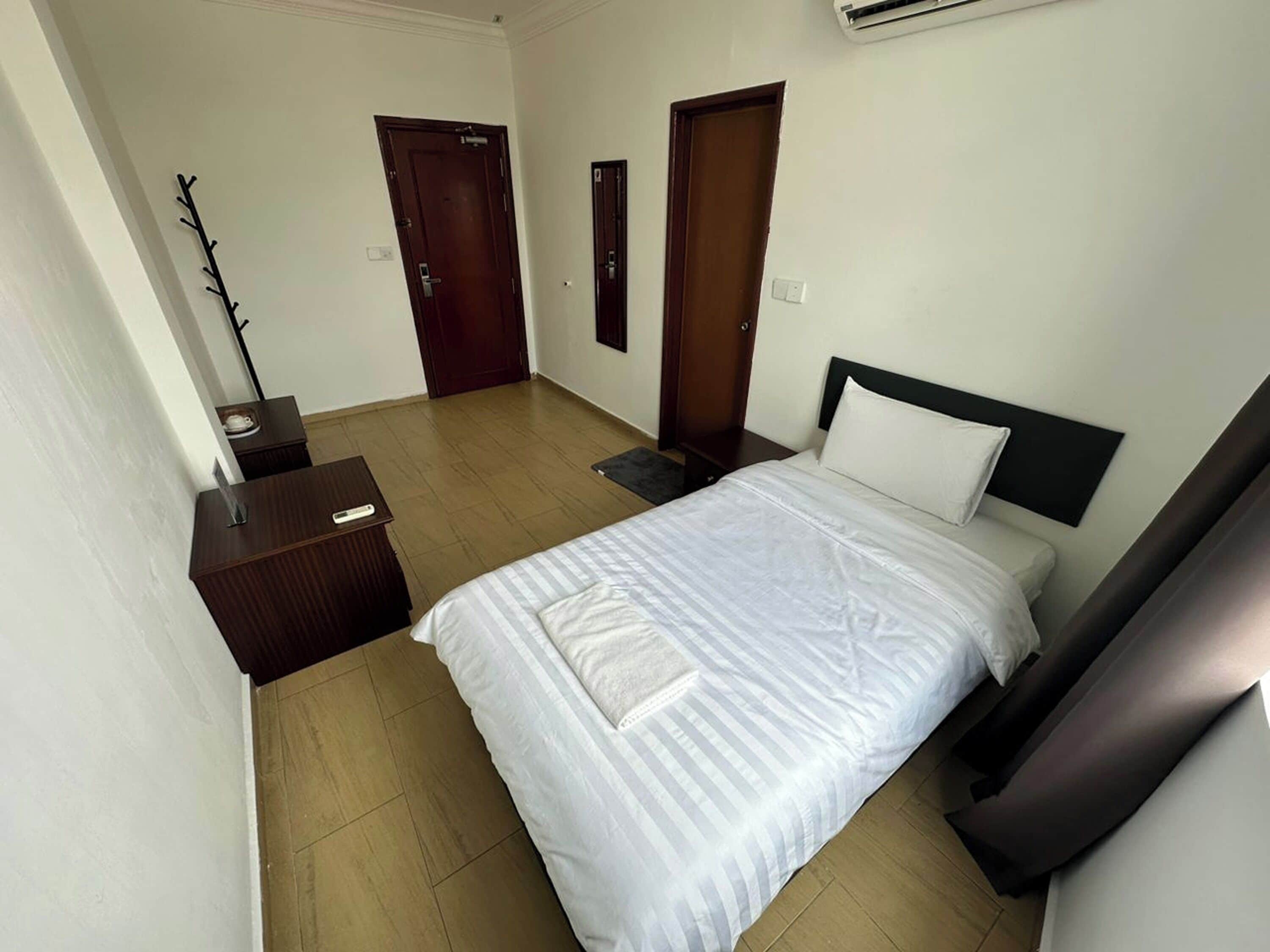 A hotel room with a bed, a nightstand, a dresser, and two doors.