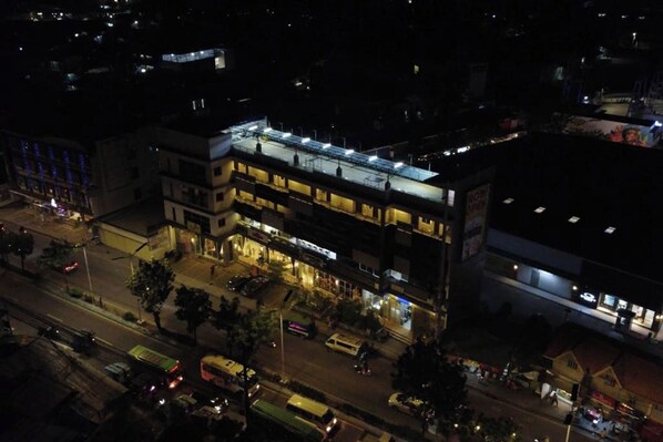 Un immeuble à plusieurs étages, avec des locaux commerciaux au rez-de-chaussée et des logements ou des bureaux aux étages supérieurs.