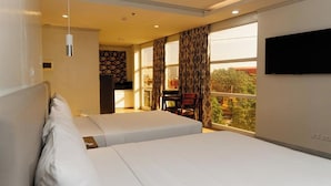 A hotel room with two beds, a TV on the wall, and a balcony with a view. - Madison Suites Mactan Cebu (Lapu-Lapu)