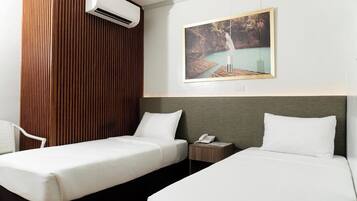 Habitación de hotel con dos camas, un panel decorativo de madera, un equipo de aire acondicionado, una mesita de noche con teléfono y un cuadro con una cascada.