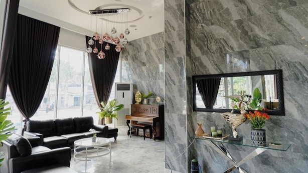 A modern living room with a sofa, coffee table, piano, and a large mirror. - Madison Suites Mactan Cebu (Lapu-Lapu)