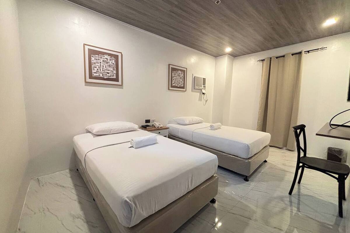 Ein Hotelzimmer mit zwei Betten, einem Schreibtisch und einem Stuhl.