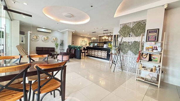 A modern hotel lobby with a reception desk, seating area, and a decorative wall with plants. - Hotel De Alexa (Maramag)
